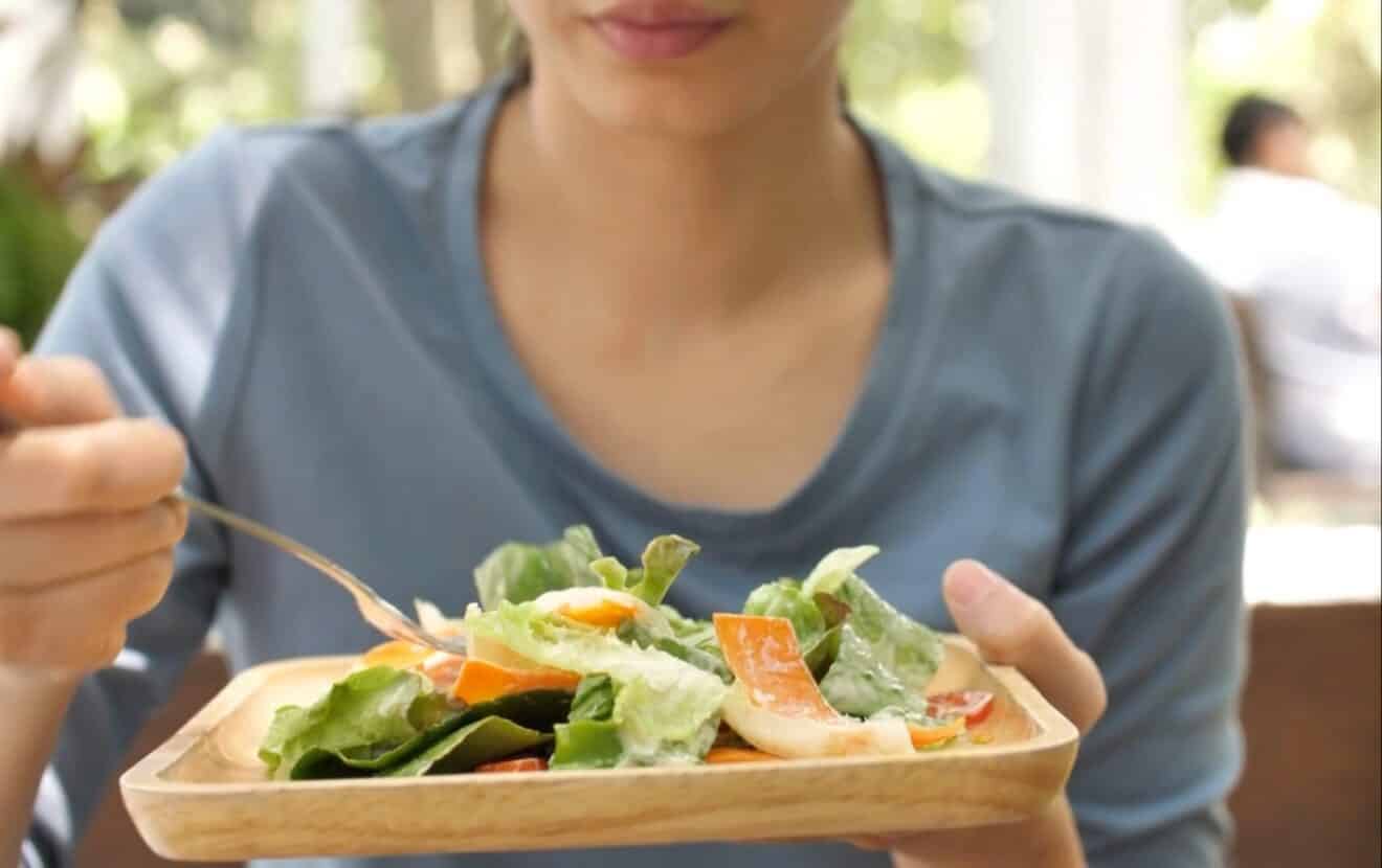 Gesund grillen: Frau isst achtsam einen frischen und leichten Salat
