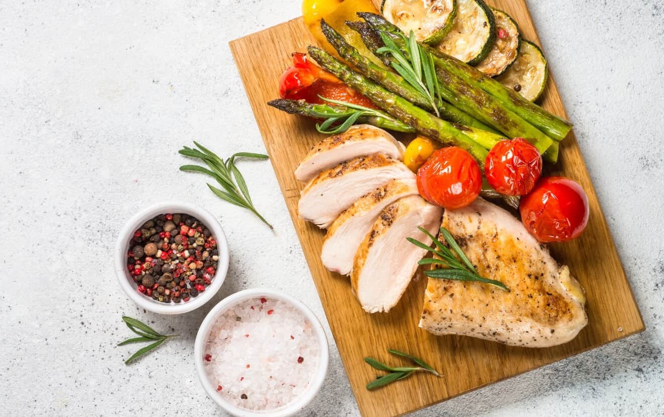 Gesund grillen: Gegrilltes Hühnchenbrustfilet und gegrilltes Gemüse - Tomaten, Zucchini, Paprika und grüner Spargel - mit frischem Rosmarin, Pfeffer und Salz verfeinert