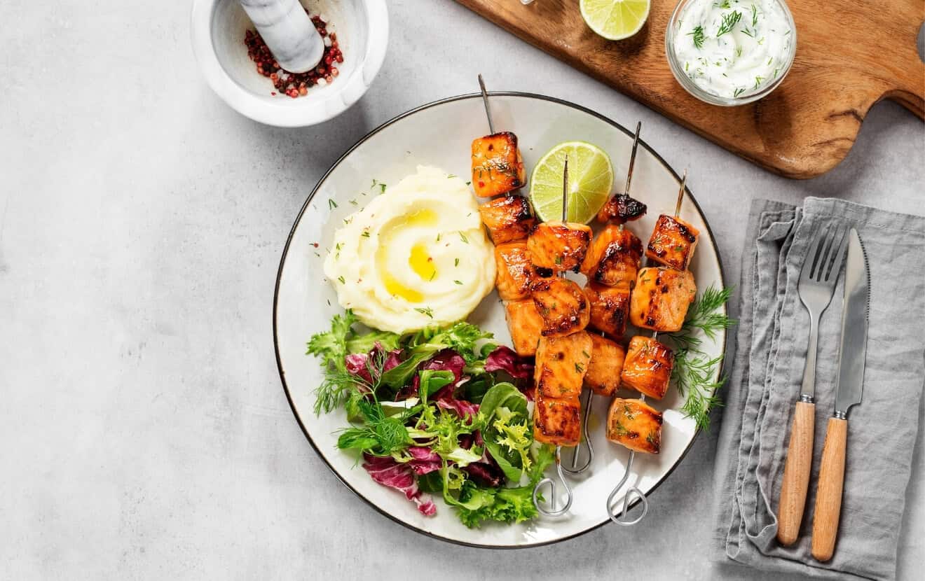 Gesund grillen: Grillteller mit Lachsspießen, frischem Salat und Dip dazu
