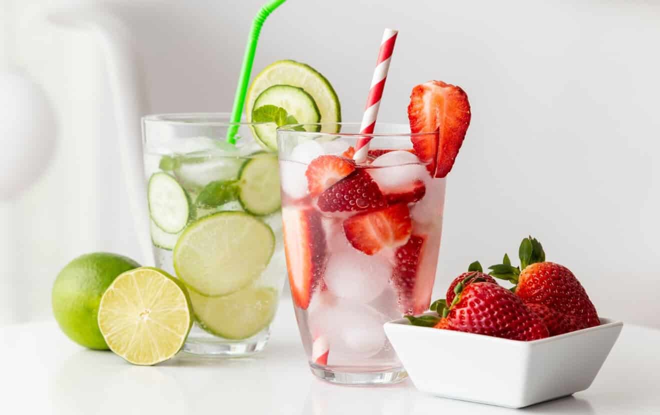 Gesund grillen: Wasser mit Gurke und Limette oder Erdbeeren und Eiswürfeln als kalorienarmes sommerlich erfrischendes Getränk für die Grillparty