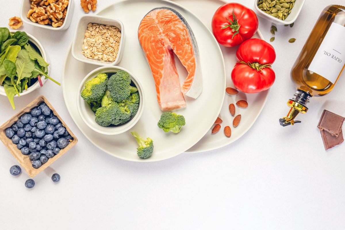 Langfristig abnehmen ohne Diät: Eine Auswahl an gesunden Lebensmittel mit Eiweiß und Vitaminen wie Lachs, Brokkoli, Haferflocken, Tomaten, Blaubeeren, Spinat und Walnüsse.