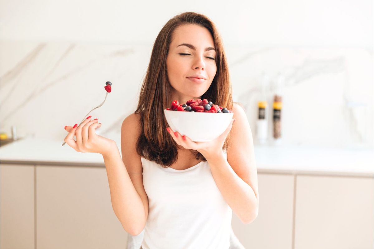 Gesund abnehmen ohne Diät: Eine Frau genießt eine Schüssel mit gesunden Beeren.