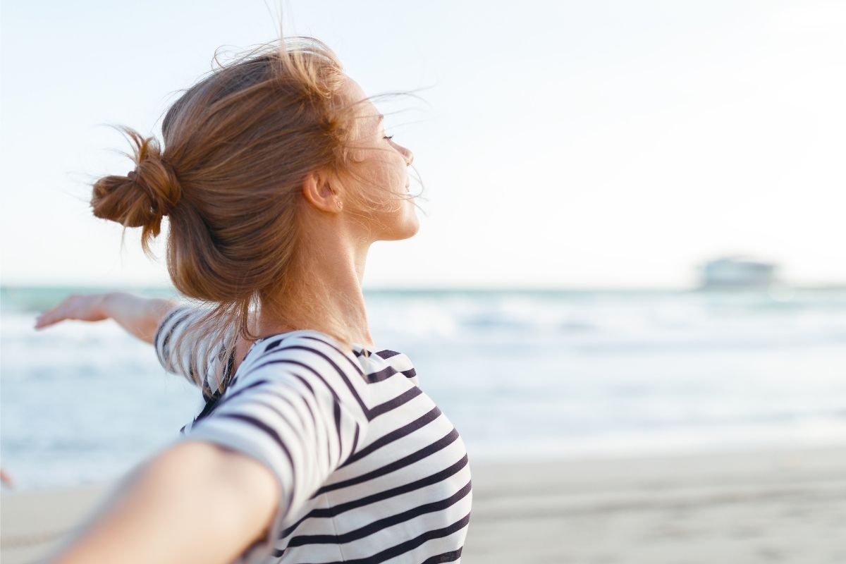 Frau am Strand fühlt sich wohl: Ein Stoffwechsel Reset sorgt für ein Rundum gutes Körpergefühl.